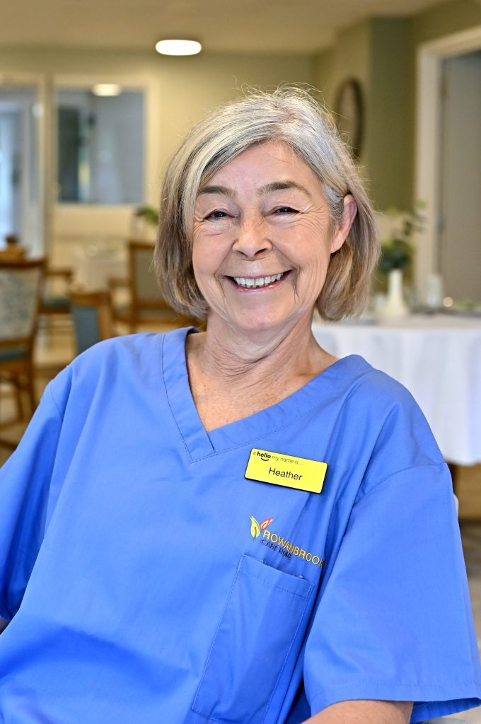 woman with grey bob smiling in blue nurses uniform