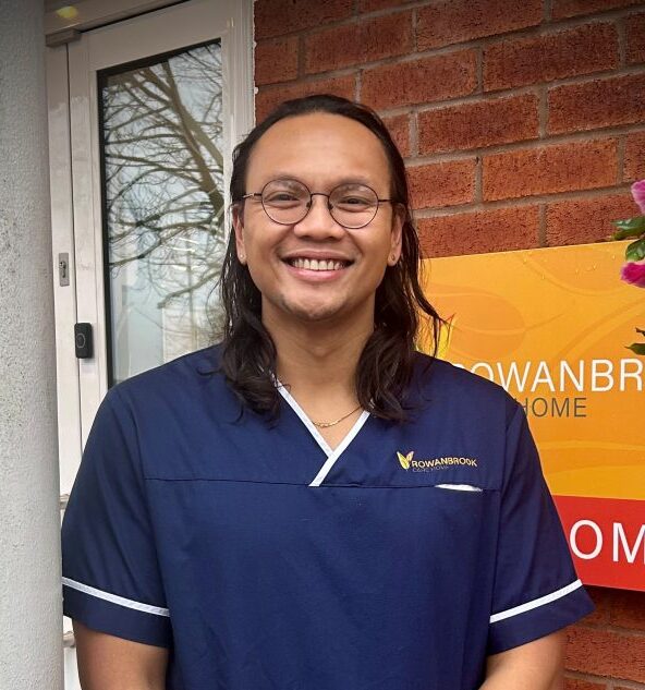 man in dark blue nurses uniform smiling